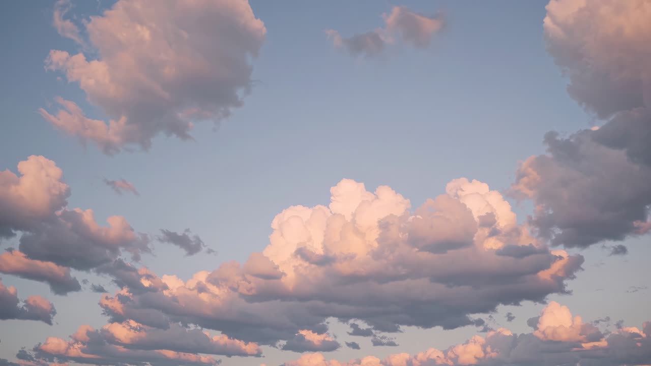 A serene video of fluffy clouds at sunset, captured from a low angle, showcasing soft pastel hues