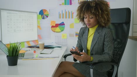 Charming-businesswoman-using-teléfono-at-workplace