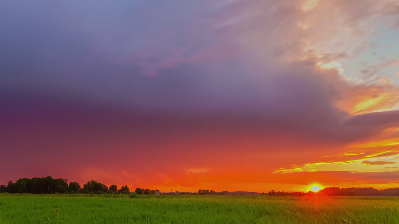 시골의 푸른 들판 위에 화려한 일몰 하늘