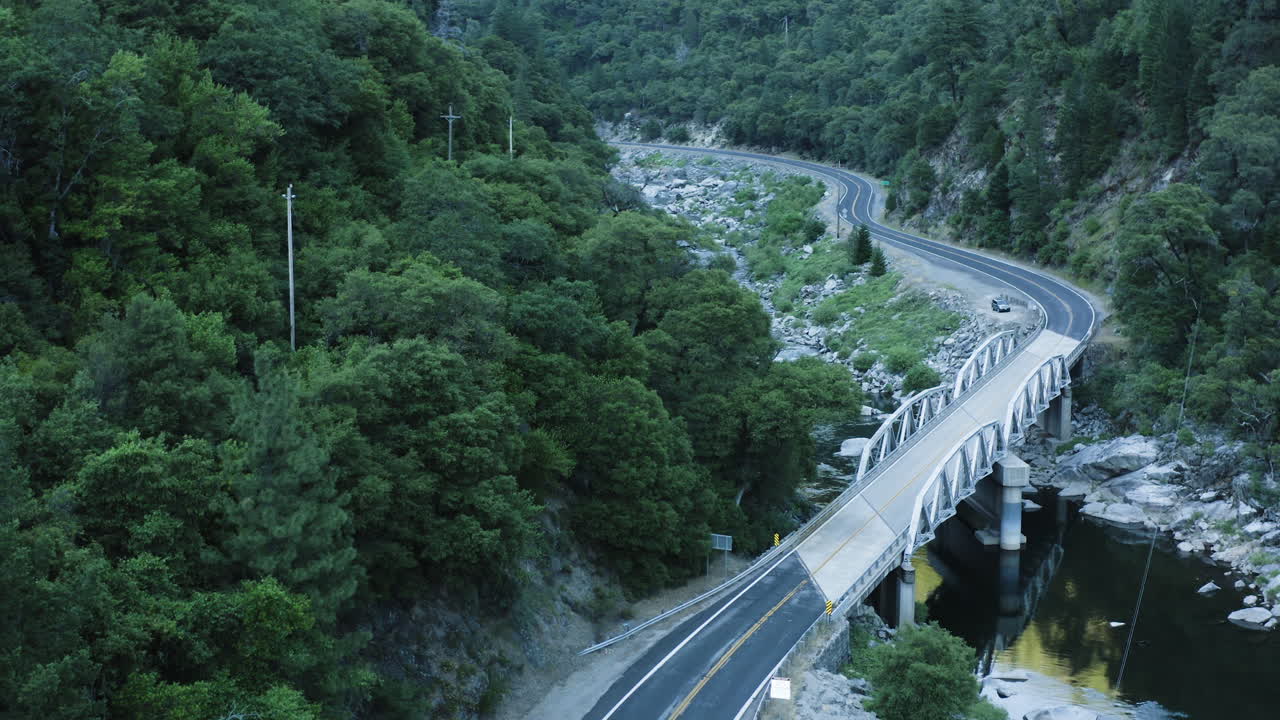 푸른 나무와 강이 있는 계곡의 시골길 위로 뒤로 날아가는 공중