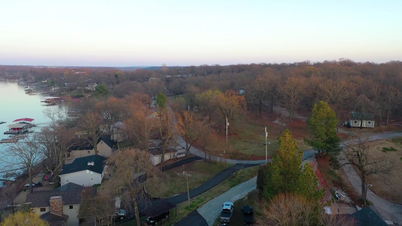 Droneoptagelser over Bull Shoals Lake, Arkansas og Missouri, med roligt blåt vand, søhuse, overdækkede anløbsbroer, skovklædt kystlinje og stille vige i varmt solnedgangslys.