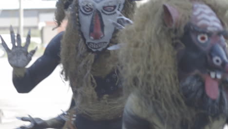 a group of indigenous black people wearing masks and dancing cheerfully while people taking photos of them