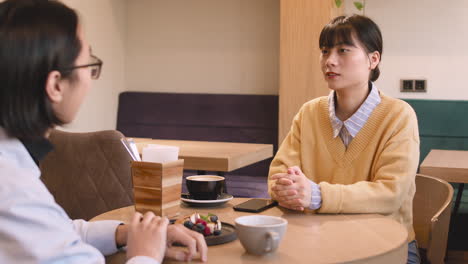 two friends talking together while sitting at table in a coffee shop