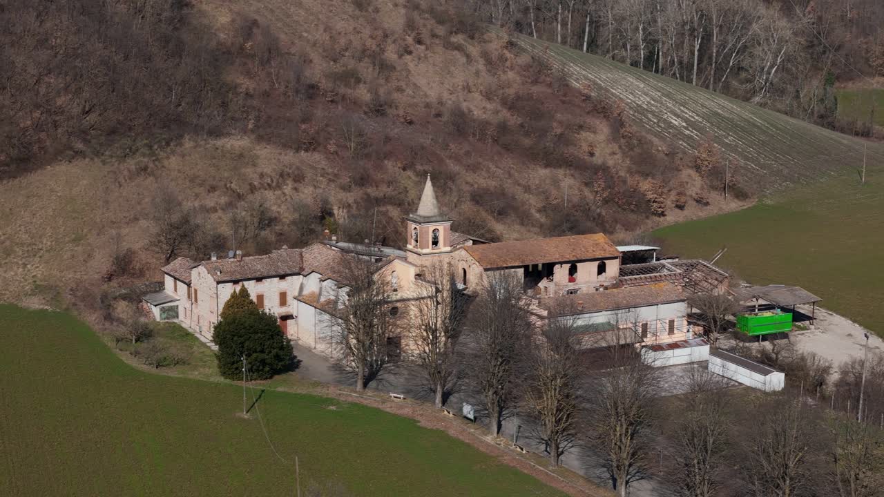 Sant Ilario Vescovo parish church and rural buildings in Chiavenna Rocchetta near Lugagnano Val d'Arda, Piacenza Province, Emilia-Romagna, Italy surrounded by farmland hills