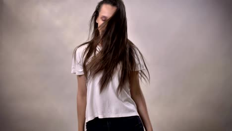 젊은 갈색 소녀는 춤추고 점프하고, 미소 짓고, 움직임 개념, 회색 배경
