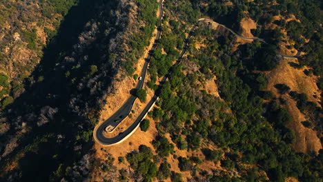 black and white car running to face each other at the dangerous loop of mountain road. bird's eye view on the rock with road on in sunny california.