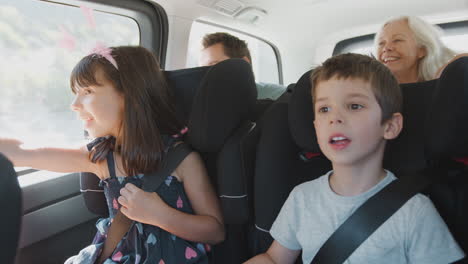 Multi-Generation-Family-Sitting-In-Back-Of-People-Carrier-Being-Driven-To-Vacation