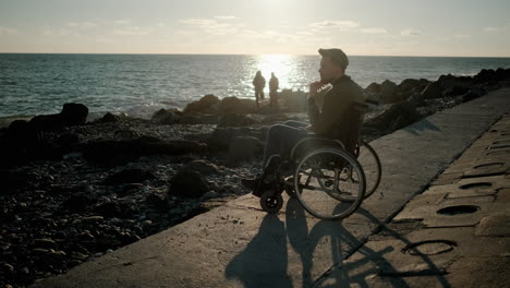 disabled man contemplating the sunset on the beach