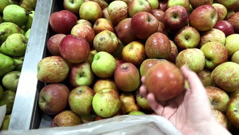 Woman-is-choosing-the-best-organic-apples-at-the-supermarket-and-putting-them-in-a-bag