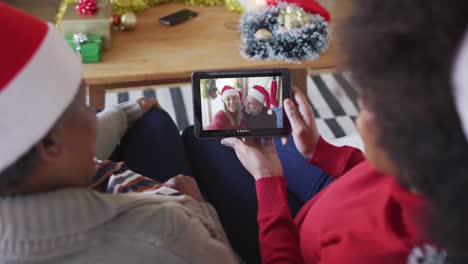 Madre-E-Hija-Afroamericanas-Usando-Una-Tableta-Para-Una-Videollamada-Navideña-Con-Una-Pareja-En-La-Pantalla