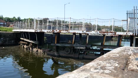 British-canal-gate-lock-waterway-low-dolly-left-towards-water-reflecting-ripples