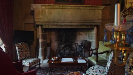 classic big fireplace area in french castle, with table and chairs, behind a candelabra