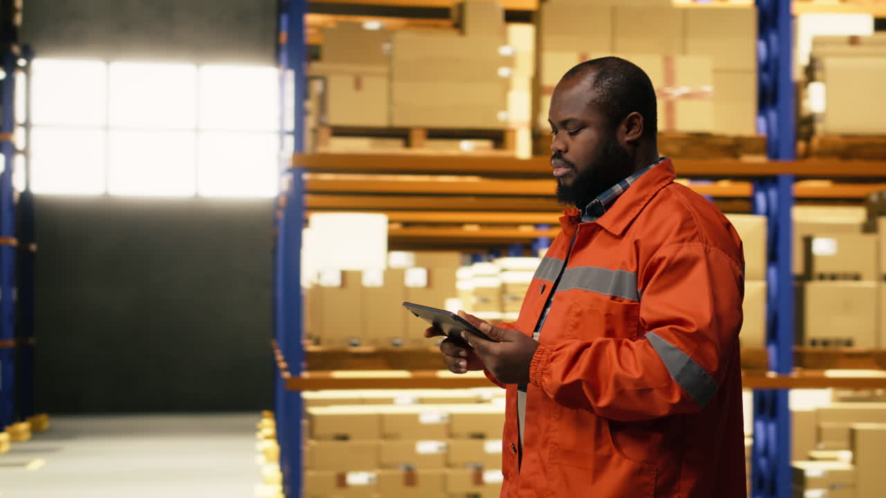 African american worker reviewing inventory data in warehouse distribution hub