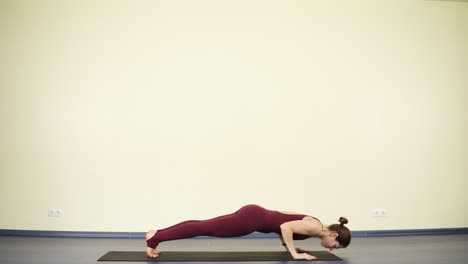 Young-spotive-woman-with-flexible-body-stretches-out-muscles-and-does-kumbhakasana-or-plank.-Keeping-healthy-beautiful-body-with-yoga-asanas.