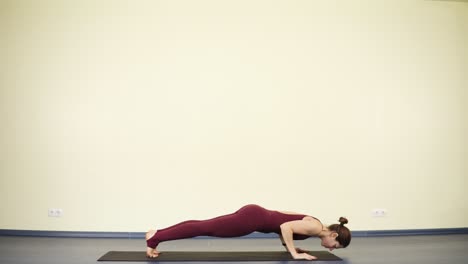 young spotive woman with flexible body stretches out muscles and does kumbhakasana or plank. keeping healthy beautiful body with yoga asanas.