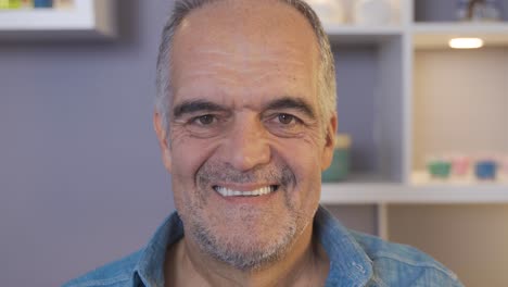 un anciano sonriendo a la cámara.