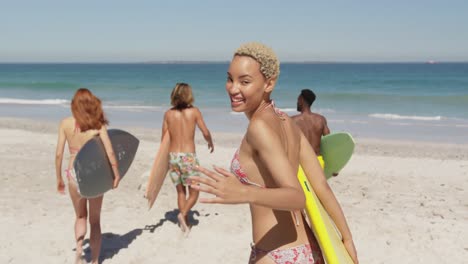 jóvenes amigos adultos en la playa llevando tablas de surf 4k
