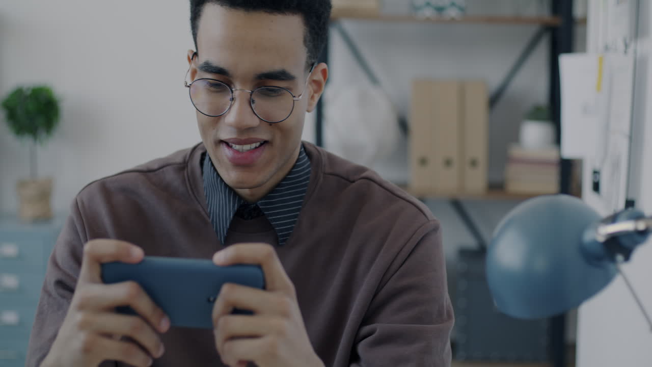 Young man playing mobile game in office