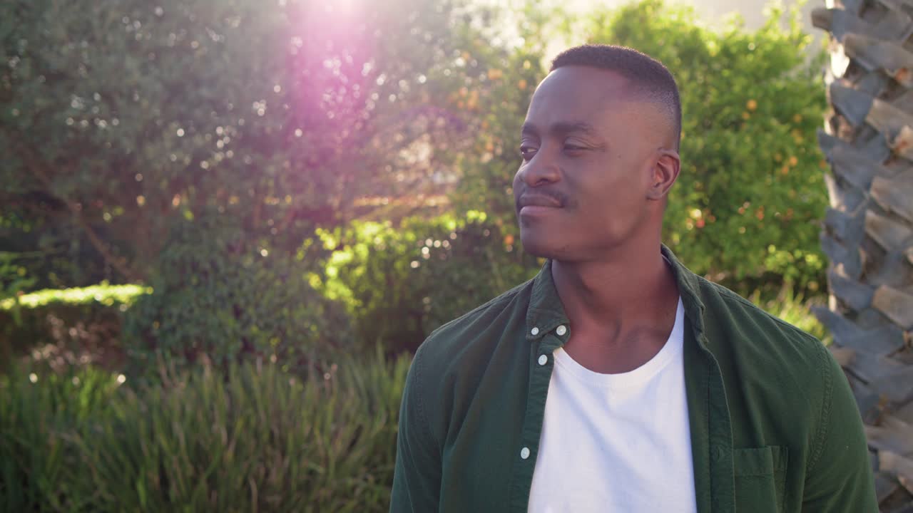 African American man reacting as camera moving in and flare shifting turning gaze smiling in garden