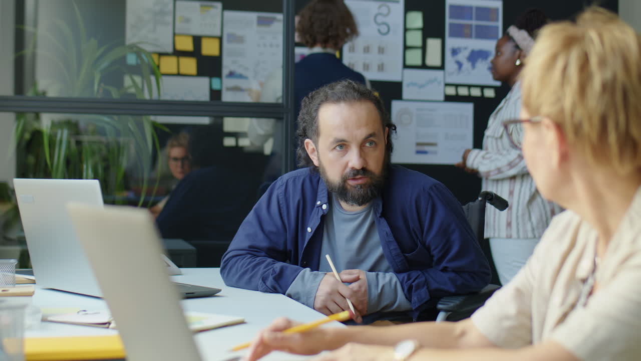 Office Worker in Wheelchair Speaking with Colleague