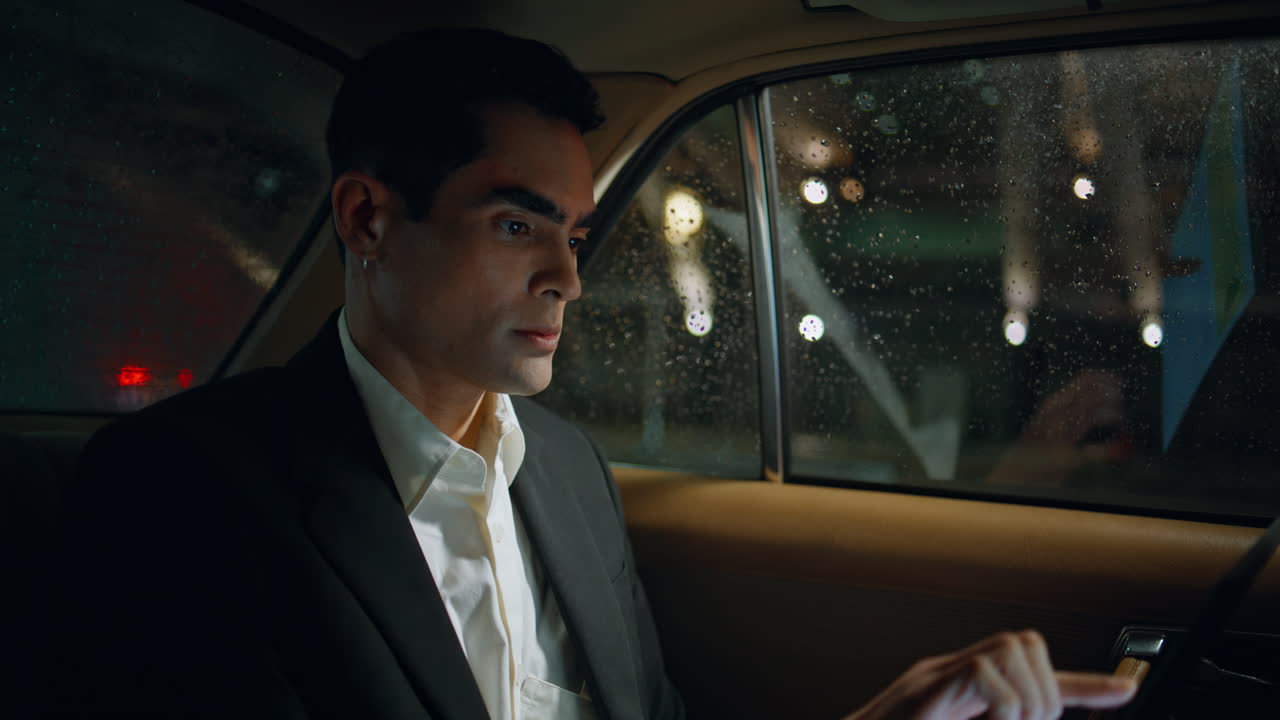 Focused passenger scrolling pad evening car closeup. Man working tablet device