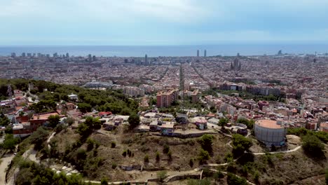 Eine-Filmische-Weitwinkel-Drohnenaufnahme-Der-Stadt-Barcelona-Mit-Blick-Auf-Die-Straße-Und-Dem-Berühmten-Turm-La-Sagrada-Familia-In-Der-Ferne