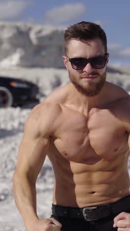 athletic man posing on camera. strong bodybuilder without shirt shows his trained body on white canyon background. muscular sportsman outdoors. vertical video