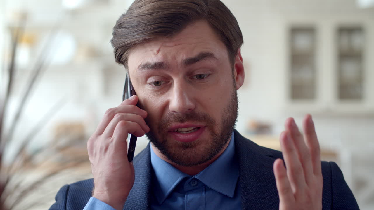 un hombre de negocios enojado hablando emocionalmente por teléfono móvil.