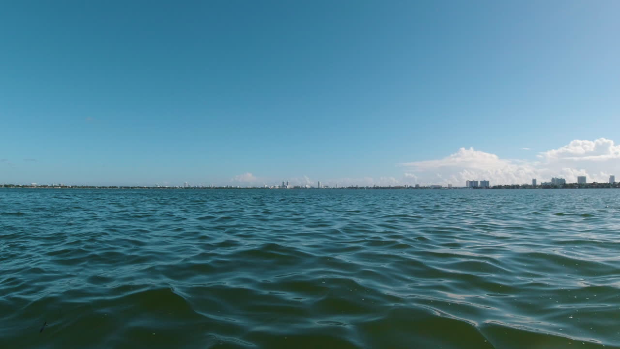 Blick vom Bug eines kleinen Wasserfahrzeugs mit der Küste Miamis auf der rechten Seite.