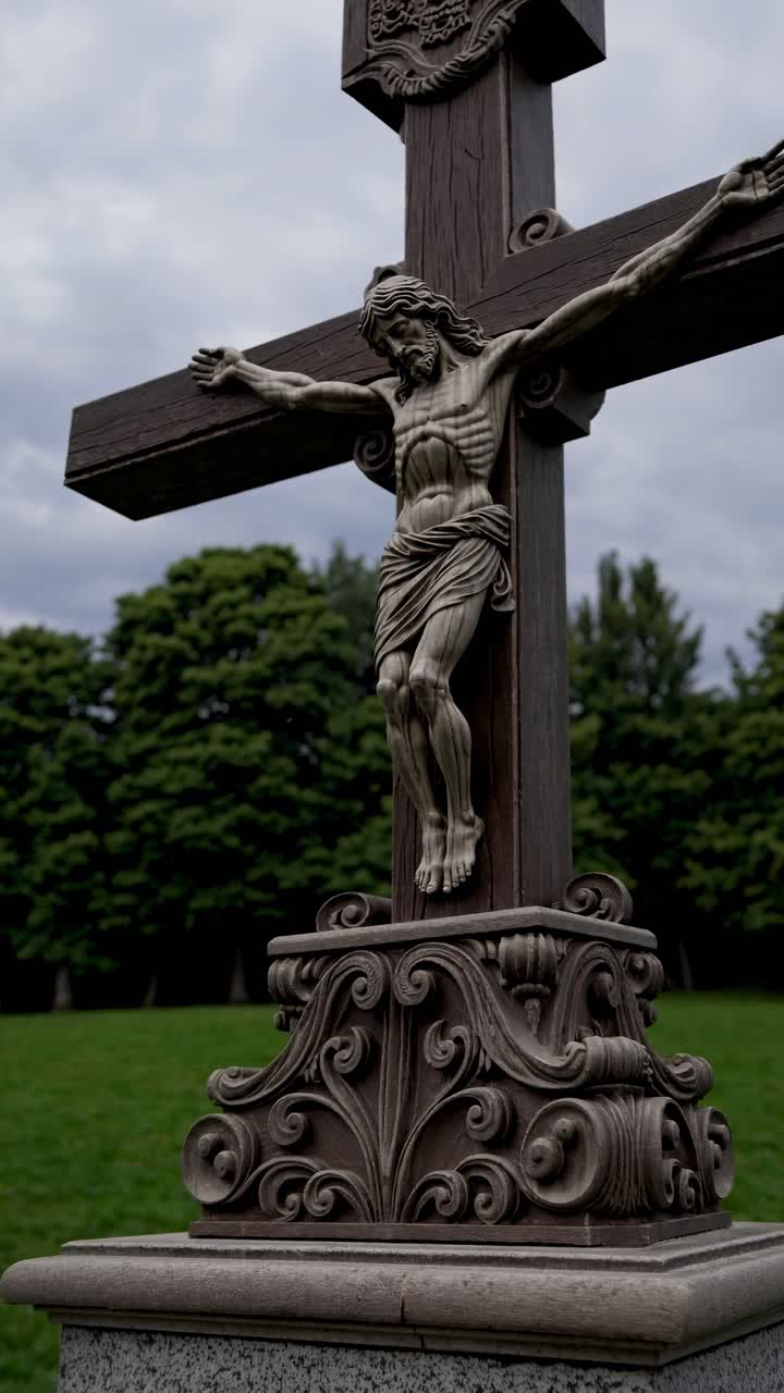 Low-angle video shot of a detailed stone crucifix against a cloudy sky, capturing the intricate