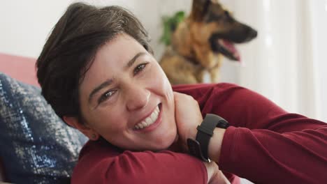 retrato de una mujer caucásica sonriendo acostada en el sofá con su perro en casa