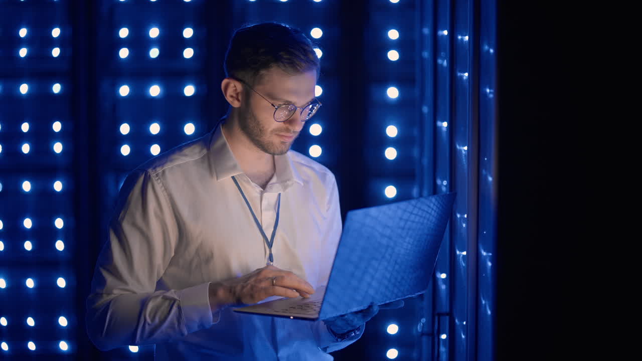Face portrait of man working in server room with laptop. technician doing a checkup in the server room. Caucasian engineer wearing grey worker jacket