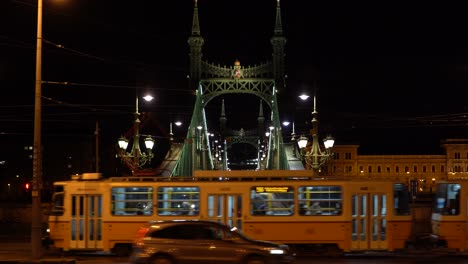 nightlife, cityscape with a bridge, a bus and a tram crossing the road at budapest