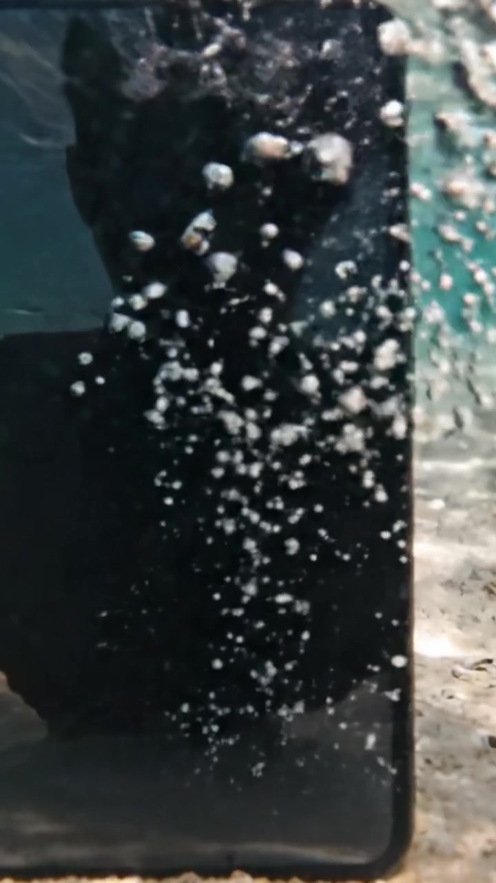 A Mysterious Underwater Scene Featuring a Reflected Shadow on a Smartphone Screen Surrounded by Bubbles and Crystal Clear Water
