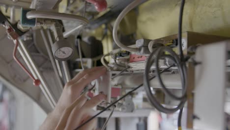 Close-up-of-two-hands-expertly-connecting-wires-and-cables-in-a-documentary-style-handheld-shot,-foreground-in-focus