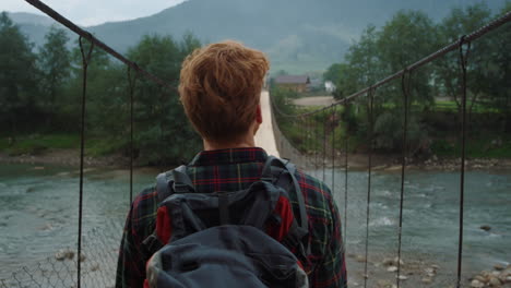 sporty hiker walk mountains on bridge close up. traveler look summer landscape.