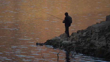 fisherman on a rocky shore at sunset