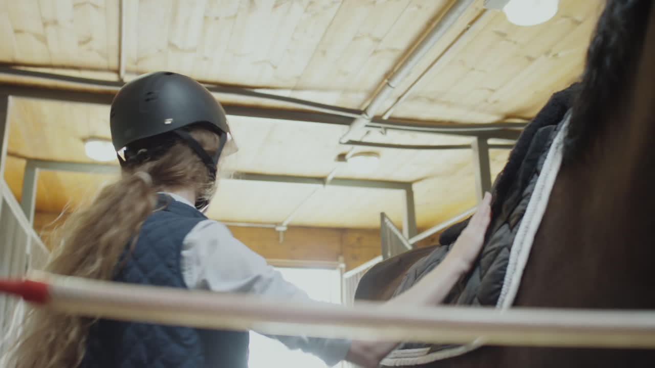 A young woman preparing a horse for riding in a stable