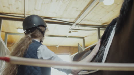 a young woman preparing a horse for riding in a stable