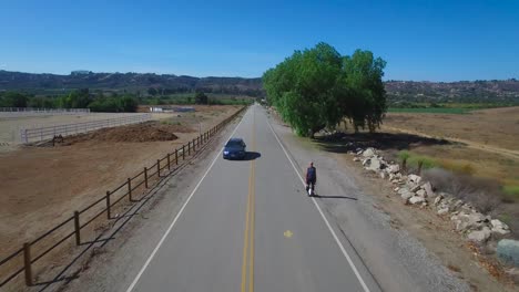 aerial footage following a man riding an electric unicycle down a road in california