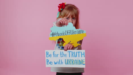 Toddler-Ukrainian-girl-alone-protesting-war-conflict-raises-inscription-massage-Hands-Off-Ukraine