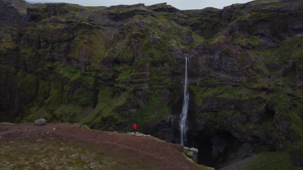vista panorámica de la cascada del cañón toma de un excursionista de chaqueta roja admirando la vista del cañón verde y la cascada