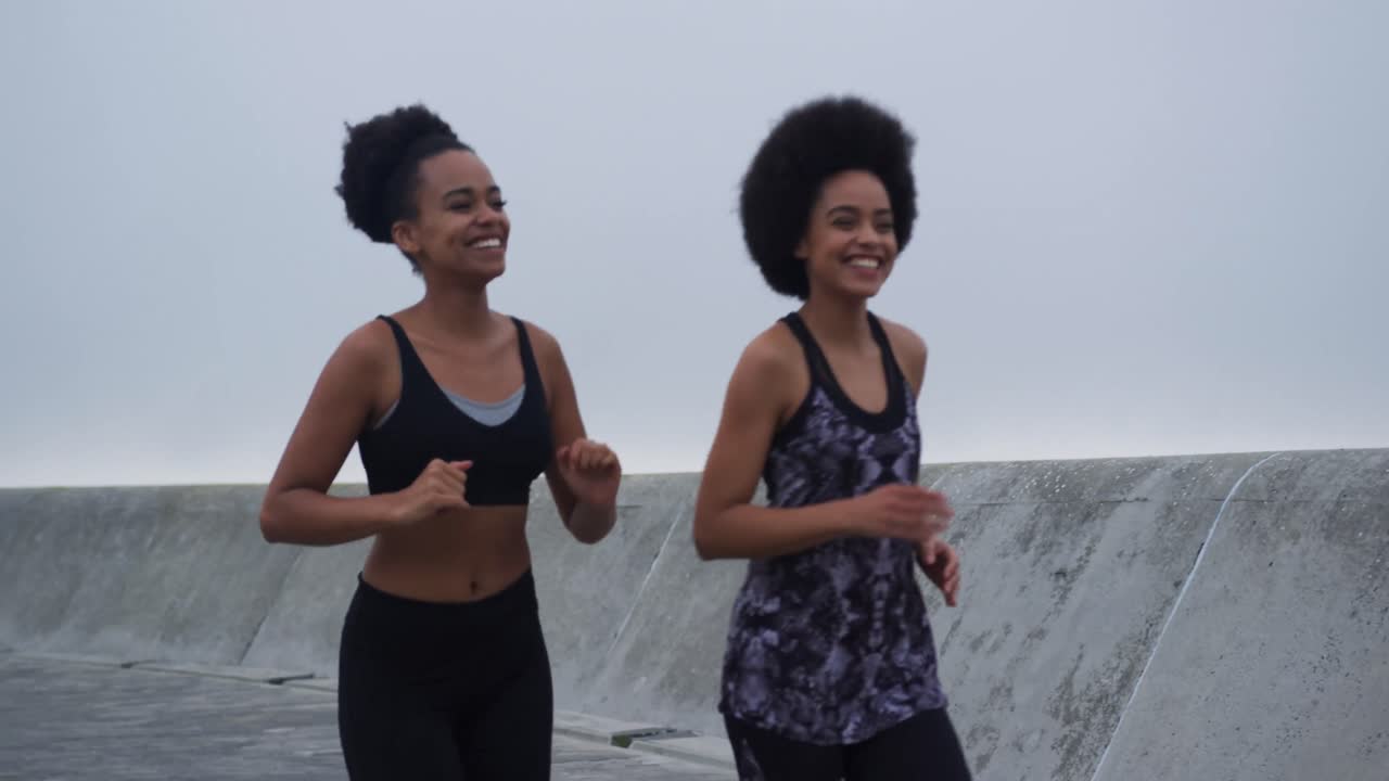 Two mixed race women running on docks