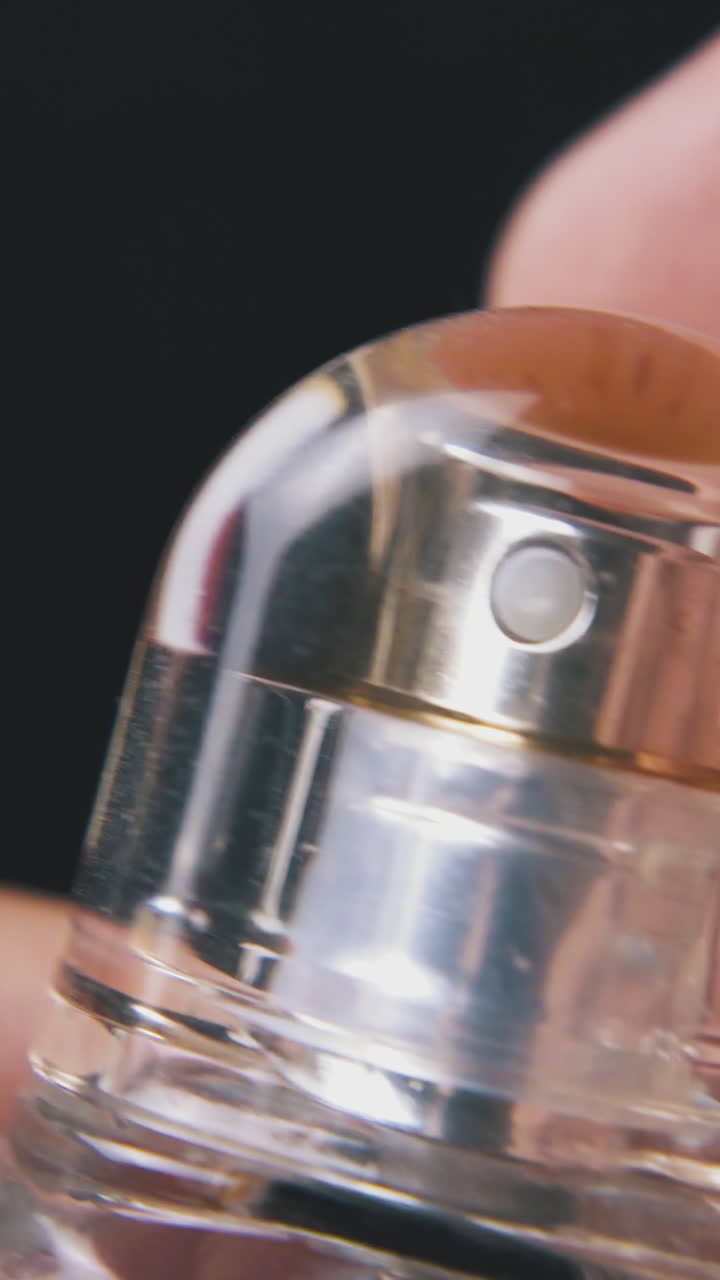 man sprays and closes women perfume water in little glass bottle on dark background extreme close view