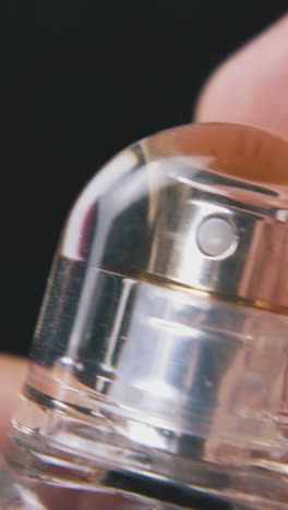 man sprays and closes women perfume water in little glass bottle on dark background extreme close view
