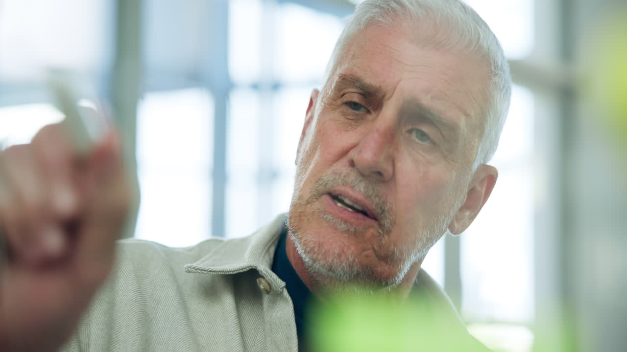 Mature Man Speaking and Writing on a Whiteboard in an Office