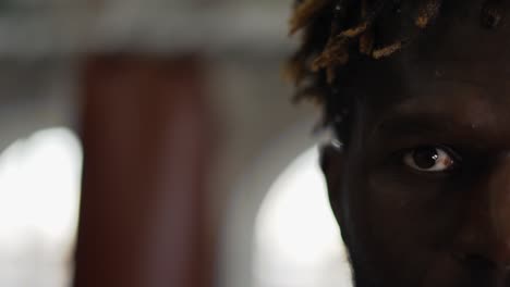 cropped view of african american boxer with boxing pear on background looking to the camera