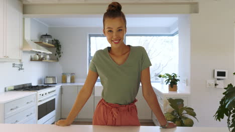 smiling woman in modern kitchen enjoying morning sunlight through window, at home