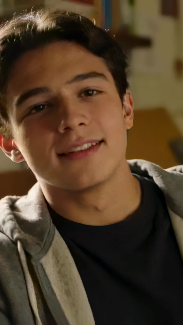Video verticale: Ragazzo adolescente sorridente che reagisce a un commento fuori campo, indicando in camera da letto, con felpa con cappuccio.