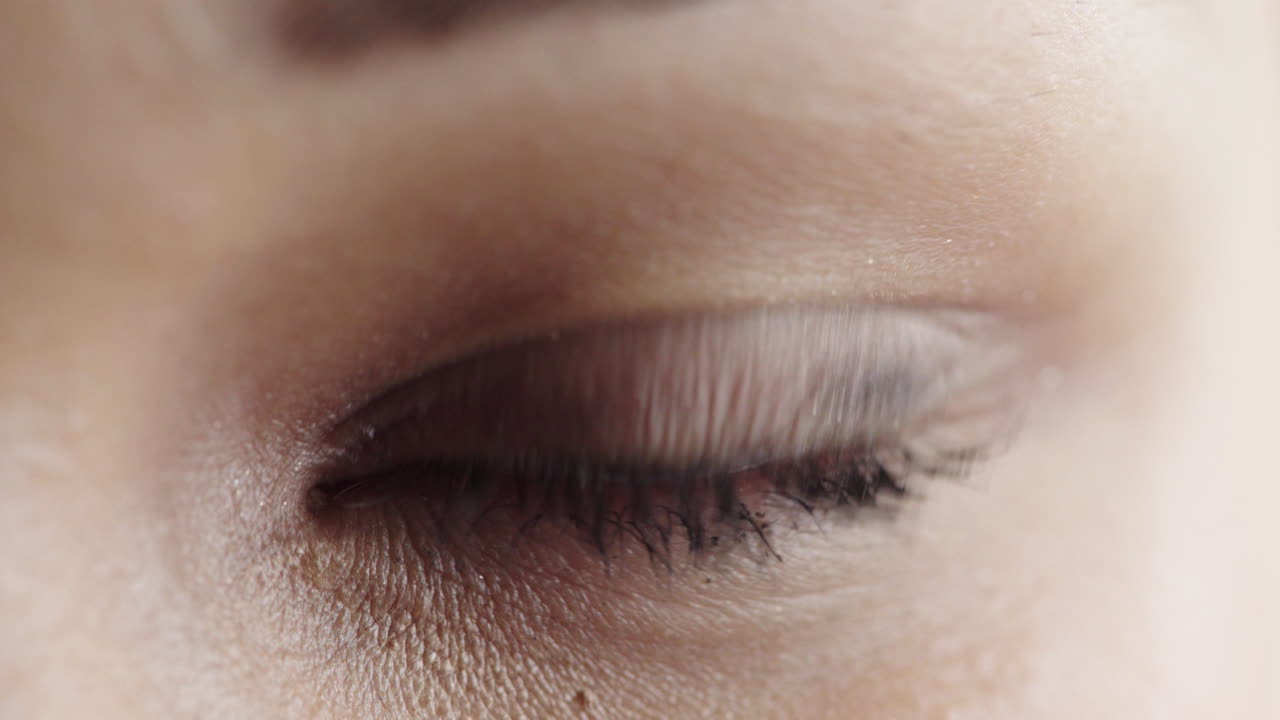 mujer joven que abre los ojos con maquillaje elegante mirando a la cámara parpadeando cosméticos de belleza femeninos